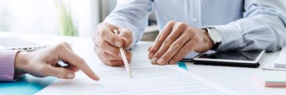 Two people having a discussion and pointing to a piece of paper related to their business.